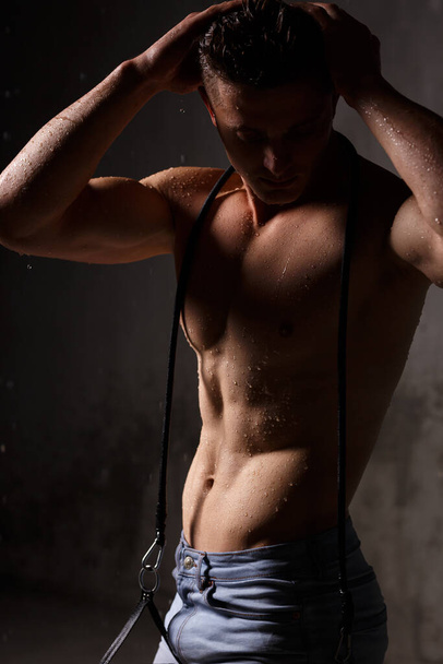 Bodybuilder se chlubí svaly a postava ve studiu v dešti. - Fotografie, Obrázek
