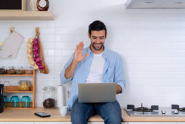 Handsome man using a laptop pc in the kitchen, calling online indoor, business webinar training, studying online. Gain new knowledge via video conferencing. Self-education, e-learning concept - Fotó, kép