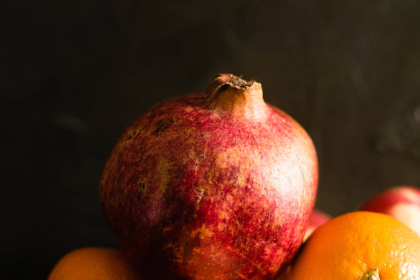 Granátové jablko na tmavém pozadí makra. Pěkná textura slupky plodu.. - Fotografie, Obrázek