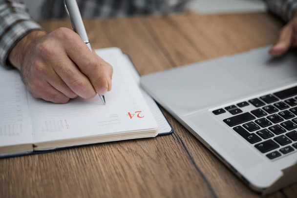 Hands writes a pen in a notebook, computer keyboard in background - Fotografie, Obrázek