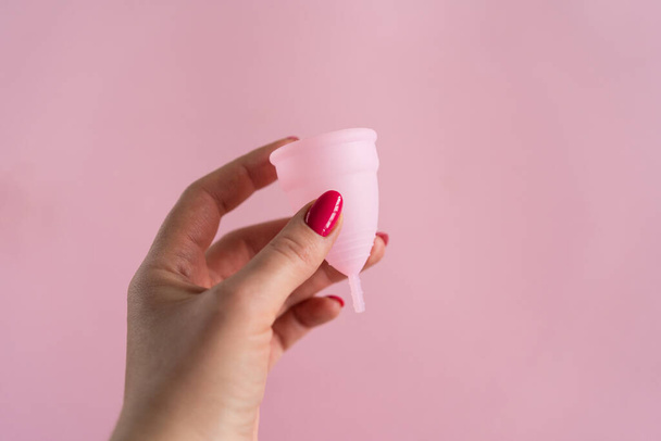 Silicone menstrual cup. Womens health and alternative hygiene. Cup with flower on a pink background. Zero waste alternatives - 写真・画像
