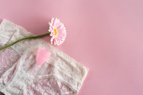 シリコン月経カップ。女性の健康と代替衛生。ピンクの背景に花とカップ。廃棄物ゼロ代替案 - 写真・画像