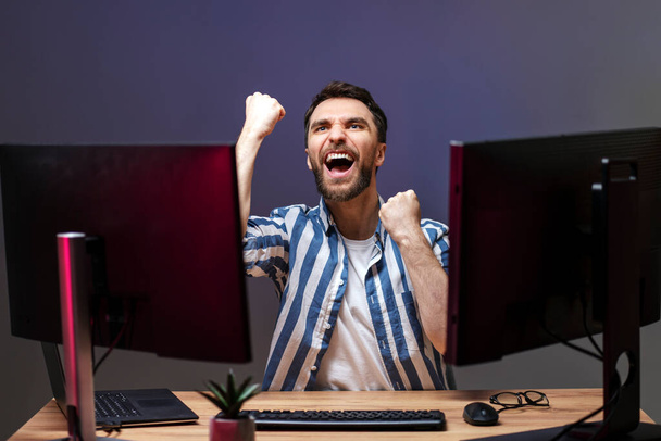 Overjoyed man gamer playing computer game at home, winning, celebration concept - Φωτογραφία, εικόνα