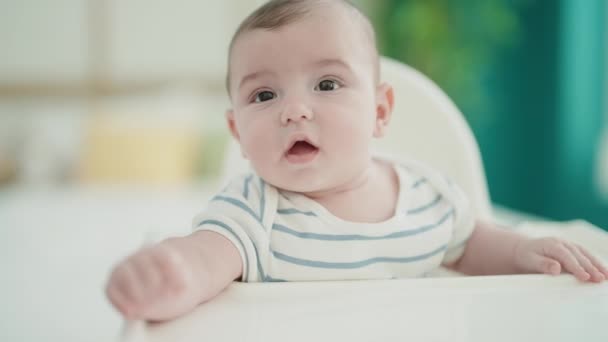 Liebenswertes kaukasisches Baby sitzt auf dem Hochstuhl im Schlafzimmer - Filmmaterial, Video