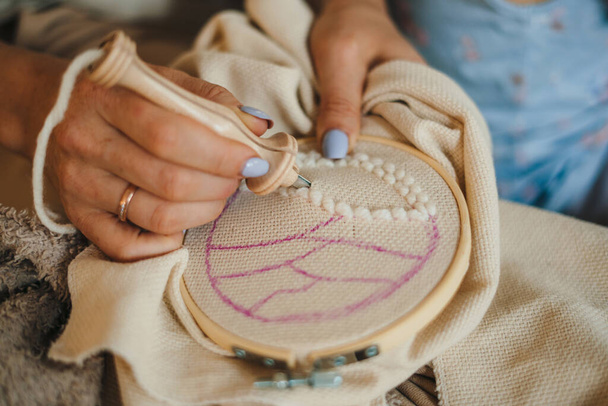 パンチ針技術で刺繍した女性の手のクローズアップ。ハンドクラフトアートを作る女性。針で作る手仕事. - 写真・画像