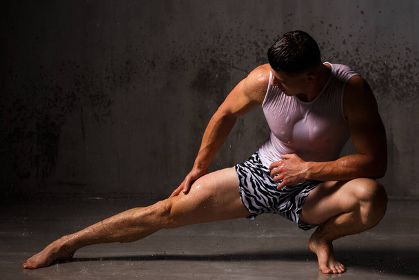 Bodybuilder flaunts his muscles and figure in the studio in the rain. - Foto, immagini