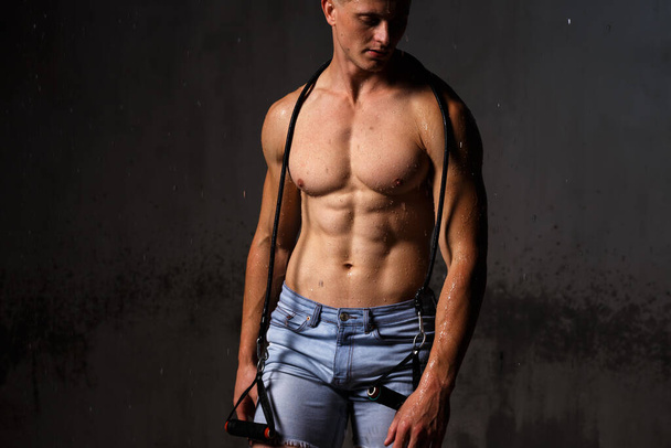 Bodybuilder affiche ses muscles et figure dans le studio sous la pluie. - Photo, image