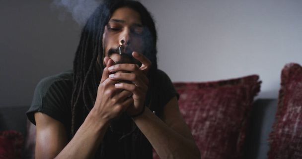 Getting lit. a young man smoking a marijuana joint at home - Foto, afbeelding