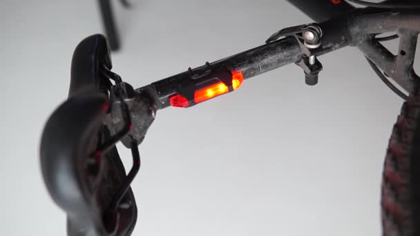 Blisko widok czerwonego światła bezpieczeństwa przymocowanego do czarnego roweru - Materiał filmowy, wideo