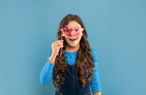 happy teen girl has curly hair hold party accessory of glasses, childhood. - Фото, зображення