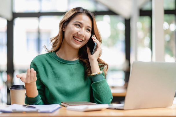 テーブルに座るカスタマーサービス電話を使用して深刻なアジアのビジネス女性,営業マネージャーは、オフィスで顧客と仕事を議論携帯電話に焦点を当てた女性 - 写真・画像