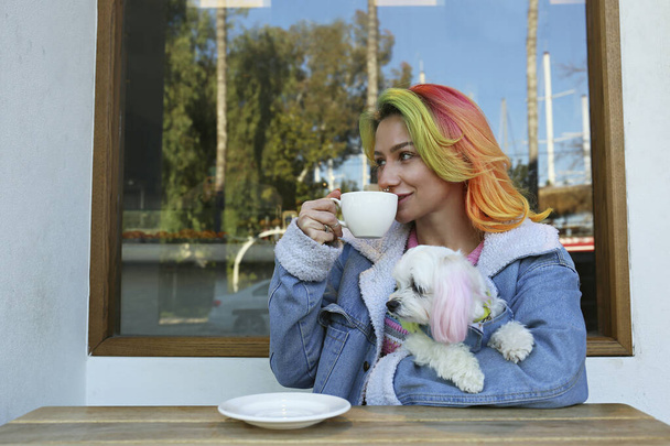 Young woman enjoying the morning cup of coffee with her maltese dog in a pet carrier backpack. Close up, copy space, background. - Φωτογραφία, εικόνα
