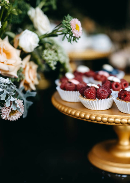 Candy bar at a party. Sweet table with blueberry cupcakes and different handmade desserts. - 写真・画像