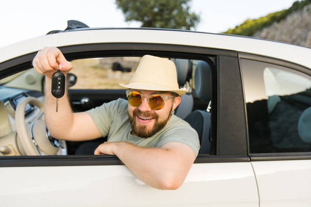 Handsome happy man showing key of new car - Rental and buy new car - Foto, Bild