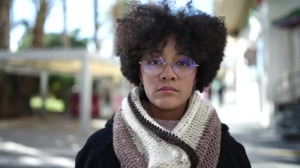 Νεαρή Αφροαμερικανή γυναίκα στέκεται με σοβαρή έκφραση γυρίζοντας πίσω περπατώντας στο δρόμο - Πλάνα, βίντεο