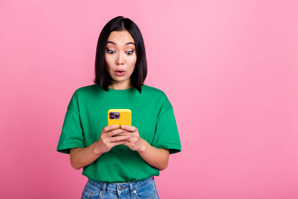 Photo of astonished girl with bob hairdo dressed green t-shirt look at smartphone online shopping isolated on pink color background. - Foto, imagen