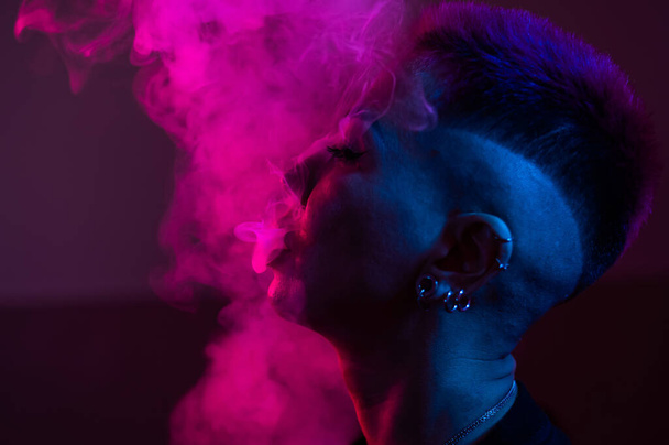 Profile Asian woman with short haircut smoking in neon light - 写真・画像