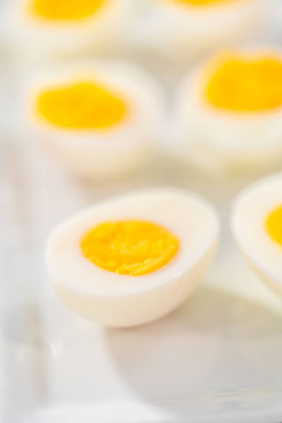 Sliced hard-boiled eggs on a white serving plate. - Foto, Bild