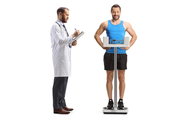 Doctor checking weight of a male athlete isolated on white background - Valokuva, kuva