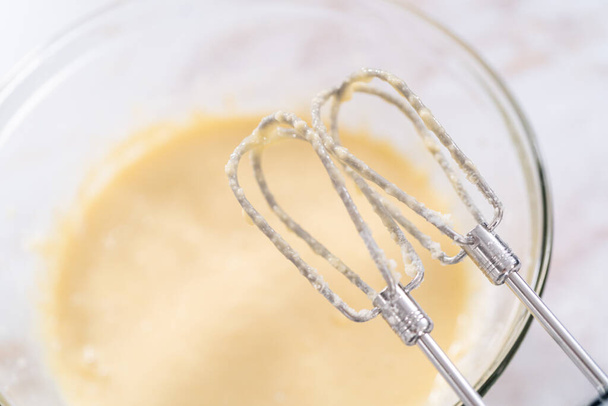 Mixing ingredients in a large glass mixing bowl to bake apple bundt cake with caramel glaze. - Fotó, kép