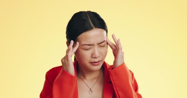 Asian woman, headache and studio with stress, migraine and hands on head to massage temple by background. Young japanese model, pain and anxiety with mental health, fatigue and burnout by backdrop. - Footage, Video