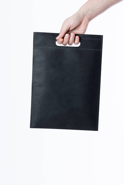 Hand of caucasian woman holding black bag with copy space on white background. Bags and fashion concept. - Foto, Imagen