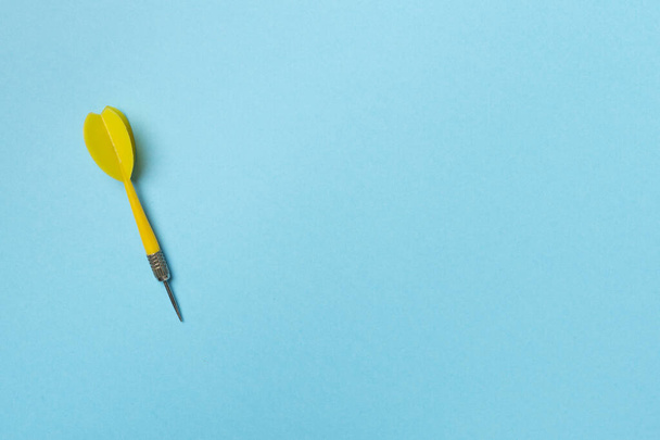 Yellow dart on color background, top view. - Foto, Imagen