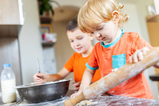 Fun family, cute kids making dough for cookies in the kitchen. - Fotó, kép