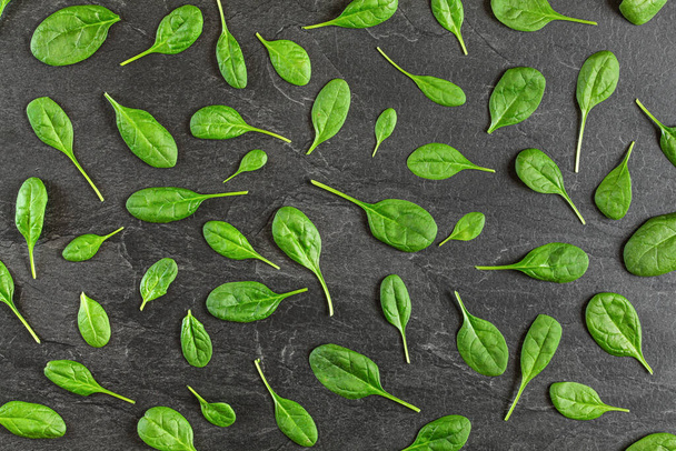 Corn salad ( Valerianella locusta ) leaves arranged in pattern over black slate like board - overhead shot. Healthy green leaf food concept - Foto, imagen