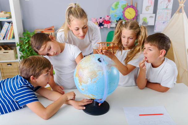 grupo de crianças bonitos sentado ao redor do globo com professor - Foto, Imagem