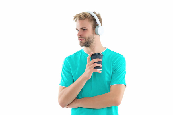 man millennial in headphones hold coffee at studio. photo of man millennial in headphones. man millennial in headphones isolated on white. man millennial in headphones on background. - Valokuva, kuva