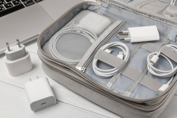 Puts wires of tablet advanced electronic equipment, phone charger in a convenient storage bag. Preparing for a business trip or vacation. Packing method for technological tools. - Fotó, kép