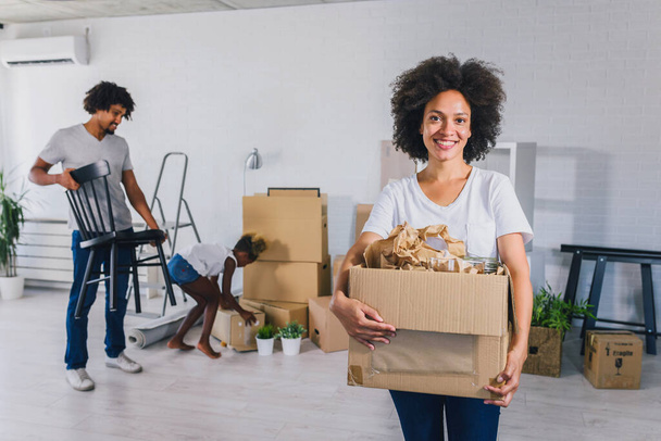 Boldog játékos afro-amerikai család költözik az új lakás, kicsomagolás, mozgó dolgokat, vásárlás ingatlan koncepció - Fotó, kép