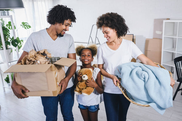 幸せな遊び心のあるアフリカ系アメリカ人の家族は、新しいアパートに移動し、梱包を解除し、物事を移動し、不動産コンセプトを購入 - 写真・画像