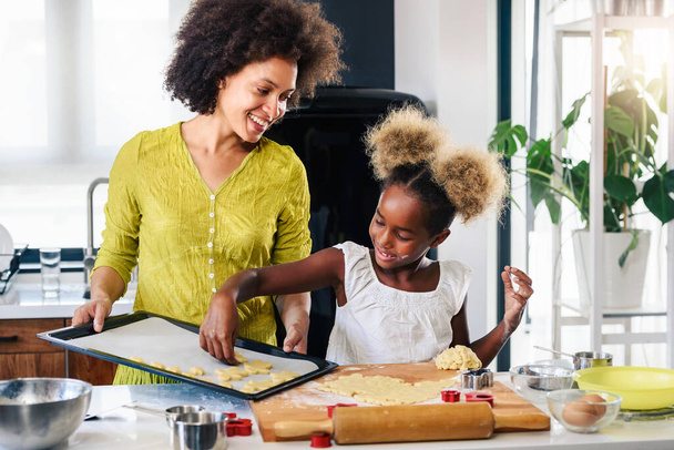 かわいいアフリカ系アメリカ人の母親と娘がクッキーを焼く  - 写真・画像