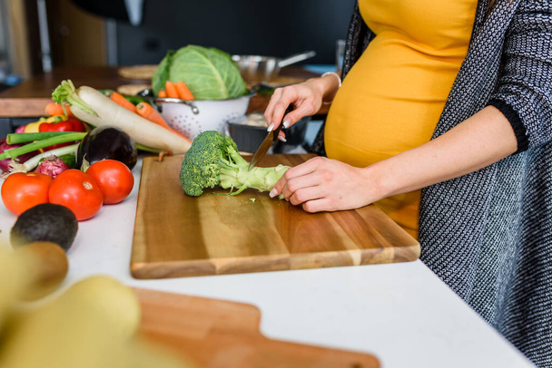 Femme enceinte coupant des légumes
  - Photo, image