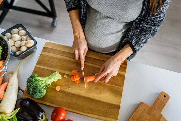 zwangere vrouw snijden groenten  - Foto, afbeelding