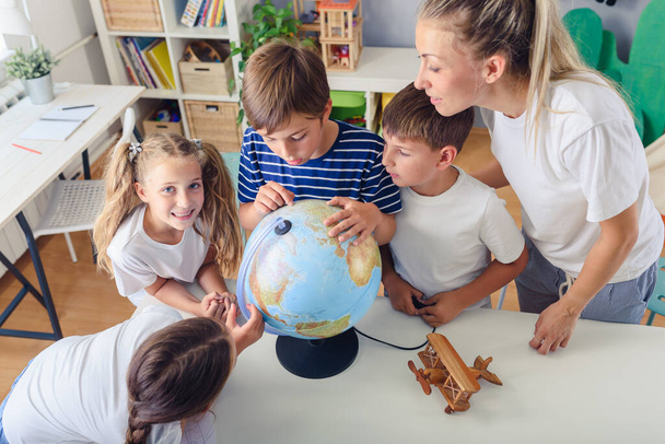 csoport a gyermekek és a tanár az osztálytermi tanulás földrajz - Fotó, kép