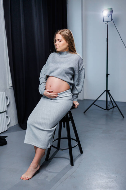 Mujer embarazada linda en suéter y falda con barriga. Feliz mujer embarazada elegante. Una mujer espera un hijo. - Foto, Imagen