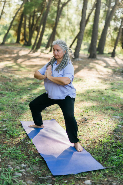 Dojrzała staruszka praktykująca jogę i tai chi na świeżym powietrzu nad morzem - koncepcja dobrego samopoczucia i wellness - Zdjęcie, obraz