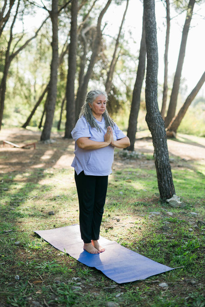 Vieille femme mature pratiquant le yoga et le tai chi en plein air au bord de la mer - concept de bien-être et de bien-être - Photo, image