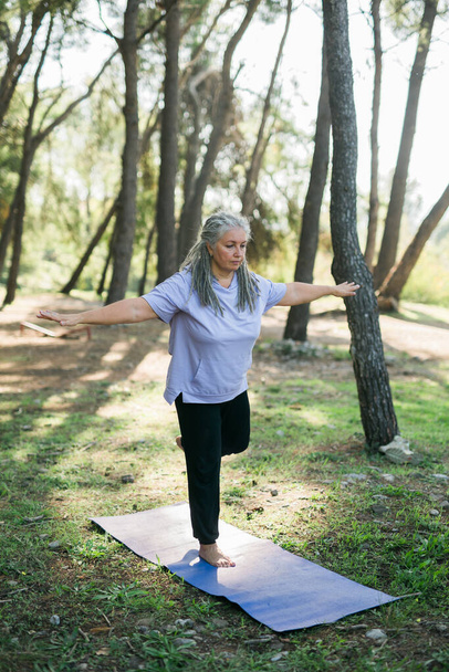 Vieille femme mature pratiquant le yoga et le tai chi en plein air au bord de la mer - concept de bien-être et de bien-être - Photo, image