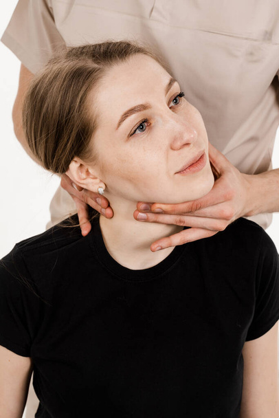 Manual therapy at physiotherapist or chiropractor. Orthopedist examining female neck and head. Manual correction of the ridge and cervical region. Rehabilitation therapy on white background - Valokuva, kuva