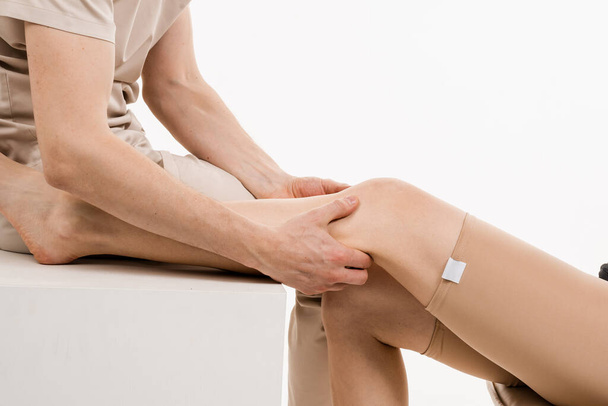 Poranění kolenního kloubu a menisku. Ortopedka se dotýká a stlačuje koleno pro posouzení objemu fyziologických pohybů. Vyšetření mobilizace kolenou - Fotografie, Obrázek