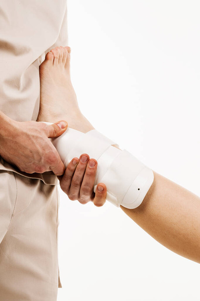 Ankle and foot external orthosis to reduce pathological mobility of ankle joints. Traumatologist puts external ankle or foot bandage on leg to recover from injuries and reduce risk of new injuries - Фото, зображення