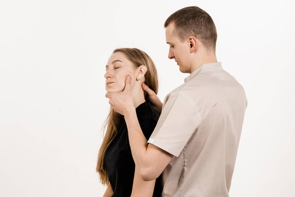 Ortopedka vyšetřuje ženský krk a hlavu. Ruční korekce hřbetu a krční oblasti. Rehabilitační terapie na bílém pozadí. Manuální terapie u fyzioterapeuta nebo chiropraktika - Fotografie, Obrázek