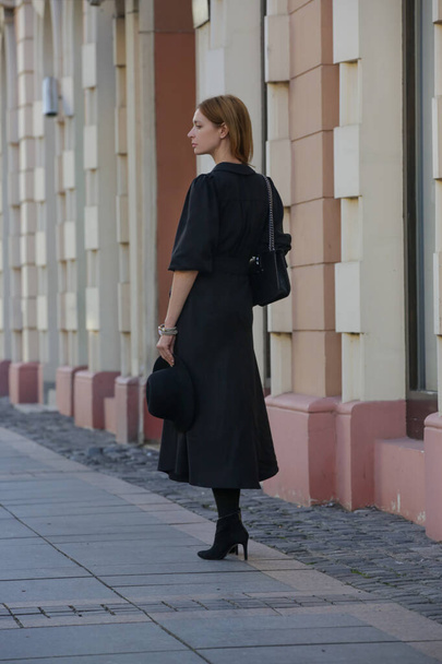 Şehir caddesinde şık sonbahar bahar kıyafetleri içinde modern, modaya uygun genç bir kadın. Siyah Midi elbiseli kadın. Moda kadın kıyafetleri, sokak modası eğilimi - Fotoğraf, Görsel