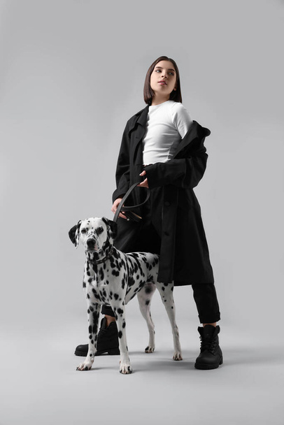 Beautiful young woman with her adorable Dalmatian dog on light grey background. Lovely pet - Fotografie, Obrázek