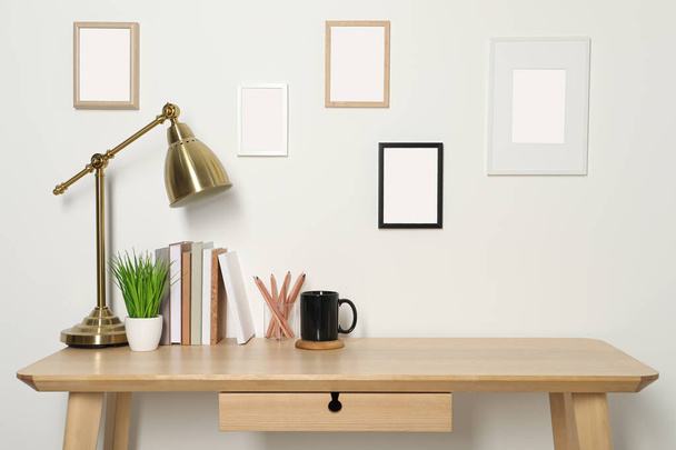Comfortable workplace with wooden desk near white wall - Photo, Image