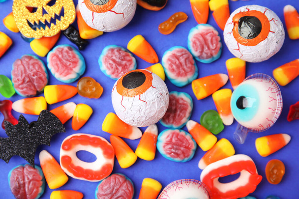 Delicious bright candies on blue background, flat lay. Halloween sweets - Zdjęcie, obraz